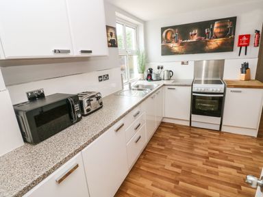 A kitchen with white cabinets and appliances including a microwave toaster and oven at Ocean House in Broad Haven