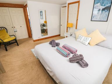 A bedroom with a bed with towels on it a chair a mirror and closets at Ocean House in Broad Haven