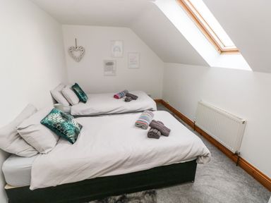 A bedroom with two single beds white bedding teal pillows and towels on the beds at Ocean House in Broad Haven