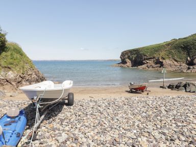 A beach with boats and stones at Ocean House in Broad Haven