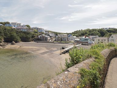 A beach scene with houses and a pier at Ocean House in Broad Haven
