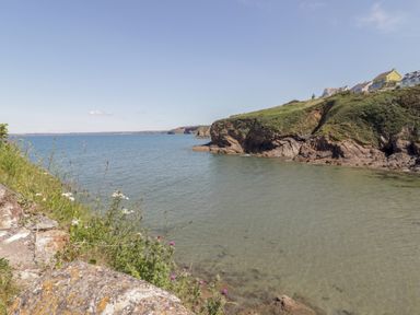 A rocky coastline with water and houses at Ocean House in Broad Haven