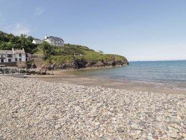 A beach with houses and a hill at Ocean House Broad Haven