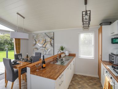 A kitchen with wooden countertops and a dining table with four chairs and tableware at Fairview Lodge in Pwllheli