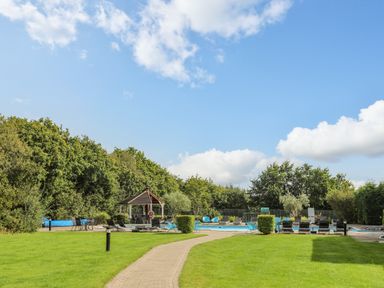 An outdoor pool area with lounge chairs tables a gazebo and green lawn at Fairview Lodge in Pwllheli