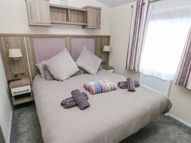 A bedroom with a double bed two bedside tables lamps and rolled towels on the bed at Starfish Retreat in Little Haven near Broad Haven