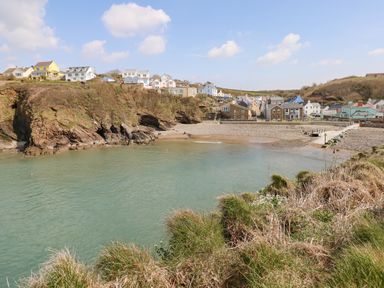 A small bay with rocky cliffs grassy foreground and houses on the hillside at Starfish Retreat in Little Haven near Broad Haven