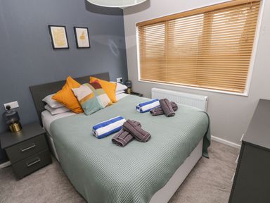 A bedroom with a bed covered with green bedding and towels on top at Driftwood Lodge Hasguard Cross near Broad Haven