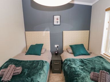 A bedroom with two single beds separated by a nightstand at Driftwood Lodge in Hasguard Cross near Broad Haven
