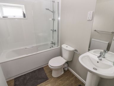 A bathroom with a bathtub shower combination a toilet and a sink at Driftwood Lodge in Hasguard Cross near Broad Haven