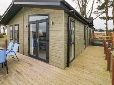 Outside view of a building with a wooden deck and blue chairs at Driftwood Lodge Hasguard Cross near Broad Haven