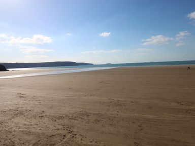 A sandy beach with a distant view of cliffs and ocean at Driftwood Lodge in Hasguard Cross near Broad Haven