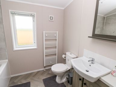 A bathroom with a toilet sink mirror window and towel rack at Ramsey in Broad Haven