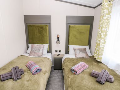 A bedroom with two single beds with green headboards and blankets and folded towels on each bed at Ramsey in Broad Haven