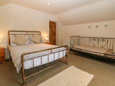 A bedroom with a double bed and a single metal framed daybed at Tyn Llwyn in Eisingrug near Harlech