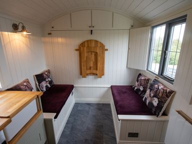 A narrow seating area with two benches and cushions with animal prints at Shepherds Hut in Dunvegan