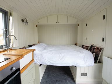 A small room with a bed, kitchen sink, oven, and wooden countertop at Shepherds Hut in Dunvegan