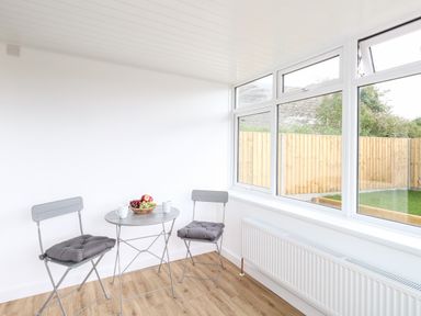 A small room with two gray chairs with cushions and a gray round table with mugs and a bowl of fruit at Cliff Barn in Burton Bradstock