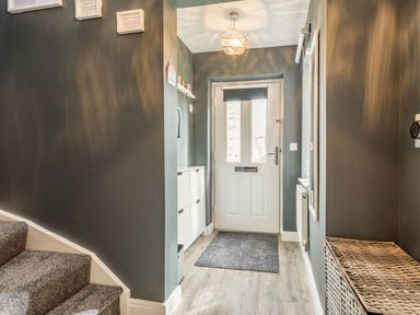 An entrance hallway with white front door stairs on the left and a wicker basket on the right at Lantern House in Filey