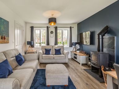 A living room with sofas and a wood stove next to a TV at Lantern House in Filey