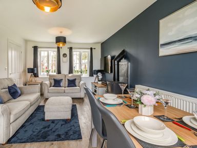 A living room with two beige sofas a blue rug and a dining table set with plates and glasses at Lantern House in Filey