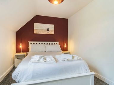 A bed with white linens and folded towels with two bedside tables and lamps in a bedroom at Lantern House in Filey