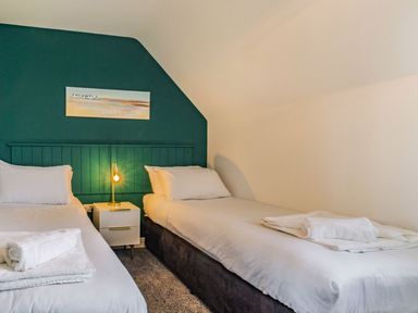 A bedroom with two single beds and a nightstand with a lamp at Lantern House in Filey