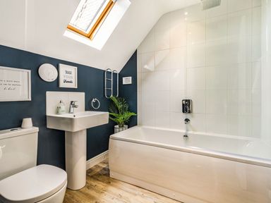 A bathroom with a toilet sink bathtub skylight and potted plant at Lantern House in Filey