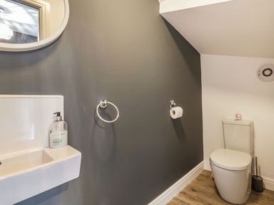 A bathroom with a toilet sink mirror soap dispenser and toilet brush at Lantern House in Filey