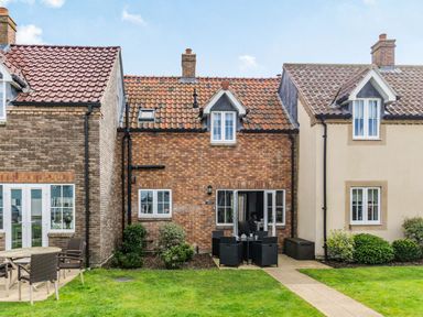 A brick house with a tiled roof and patio furniture in a garden at Lantern House in Filey