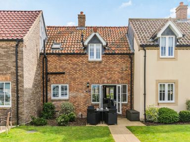 A backyard with patio furniture and an open door of a brick house at Lantern House in Filey