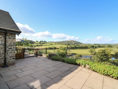 A patio with stone tiles and plants overlooking fields and hills at Pen Y Banc in Llanfaredd near Builth Wells