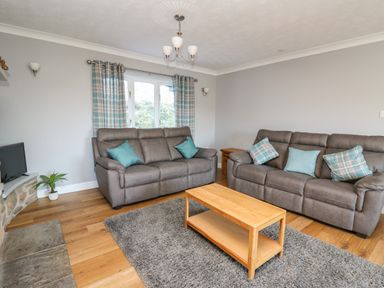 A living room with two sofas a wooden coffee table a television and plaid curtains at Pen Y Banc in Llanfaredd near Builth Wells