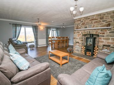 A living room and dining area with sofas a coffee table a stone fireplace and a dining table with chairs at Pen Y Banc in Llanfaredd near Builth Wells