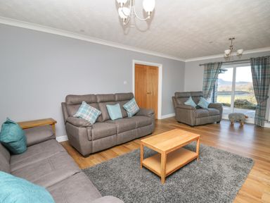 A living room with three grey sofas a wooden coffee table a grey rug and large glass doors at Pen Y Banc in Llanfaredd near Builth Wells