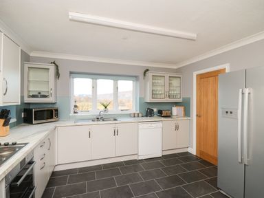 A kitchen with white cabinets a stainless steel refrigerator microwave oven and a window with a view at Pen Y Banc in Llanfaredd near Builth Wells