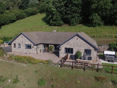 A stone house with a tiled roof patio outdoor seating hot tub and fenced garden at Pen Y Banc in Llanfaredd near Builth Wells