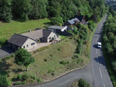 Aerial view of two houses near a curved road with surrounding trees and greenery at Pen Y Banc Llanfaredd near Builth Wells