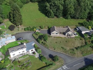 An aerial view of two houses with driveways and gardens surrounded by trees at Pen Y Banc in Llanfaredd near Builth Wells