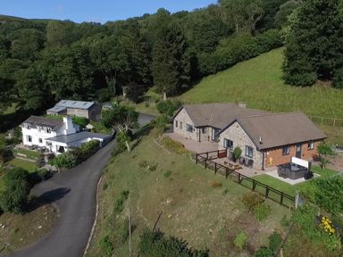 A rural property with multiple buildings surrounded by trees and grassy hills at Pen Y Banc in Llanfaredd near Builth Wells