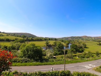 A rural landscape with a winding river green fields and a road with a slow sign at Pen Y Banc Llanfaredd near Builth Wells