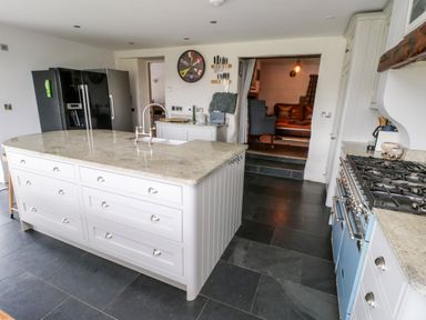 A kitchen with a central island, a gas stove, and a double refrigerator at Cae Du in Dwyran near Niwbwrch Newborough