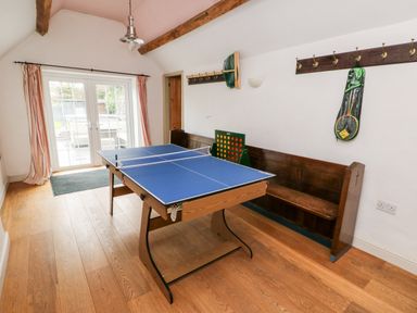 A game room with a table tennis table a wooden bench and a large connect four game at Cae Du in Dwyran near Niwbwrch Newborough