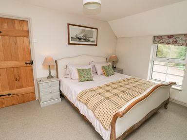 A bedroom with a double bed two bedside tables and a window at Cae Du in Dwyran near Niwbwrch Newborough