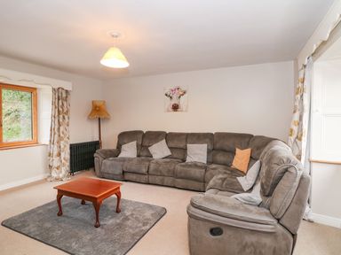 A living room with a gray sectional sofa and a wooden coffee table on a rug at Coffey's in Ballymacarbry County Waterford