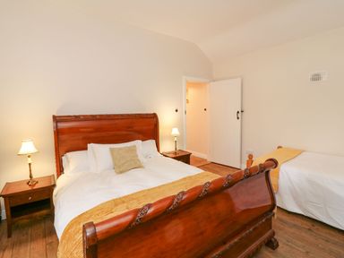 A bedroom with a wooden bed frame a bedside table with a lamp and a single bed at Coffey's in Ballymacarbry County Waterford