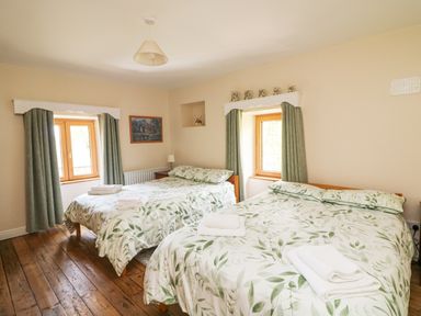 A bedroom with two beds covered with leaf patterned bedding and towels folded on top at Coffey's Ballymacarbry County Waterford