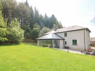 A house with a glass extension surrounded by a grass lawn and trees at Coffey's Ballymacarbry County Waterford