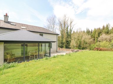 A house with a glass extension overlooking a lawn and trees at Coffey's in Ballymacarbry County Waterford