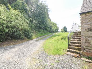 A gravel driveway beside a grassy area with stone steps and a stone building at Coffey's in Ballymacarbry County Waterford